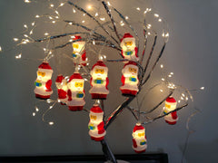 Santa string lights draped on a lit branch tree