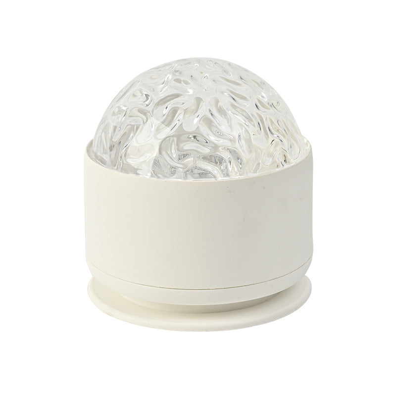 Rotating night light with a white base and clear textured dome