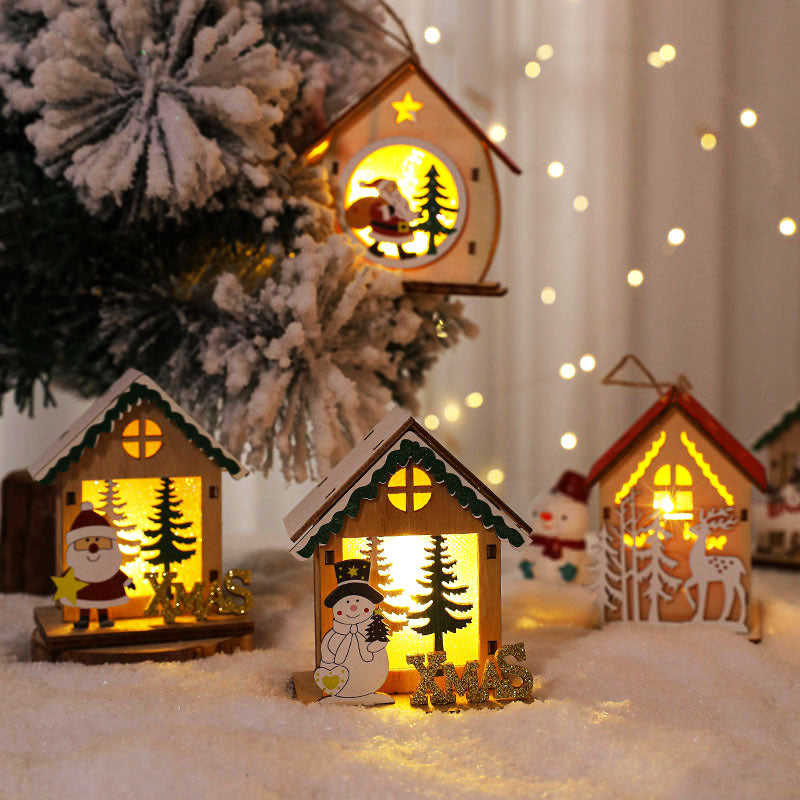 Glowing wooden Christmas houses on snow by a Christmas tree
