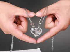 Hands holding the silver split heart couple necklaces